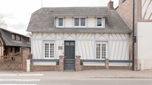 A traditional half-timbered building with a dark-colored door, a small porch, and a brick wall.