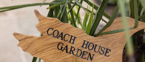Ein hölzernes Schild mit der Aufschrift 'COACH HOUSE GARDEN'.