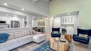A modern living room with a sofa, two armchairs, a coffee table, and a dining area with a table and chairs.