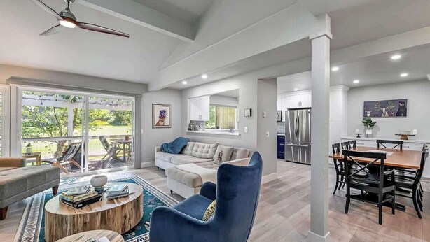 A spacious living room with a large sofa, a coffee table, and a dining area with a wooden table and chairs. - Red Fox Retreat - 37 Aspen (Blairsden)