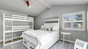 A bedroom with bunk beds, a bed with decorative pillows, a small round table, and a window with blinds. - Red Fox Retreat - 37 Aspen (Blairsden)