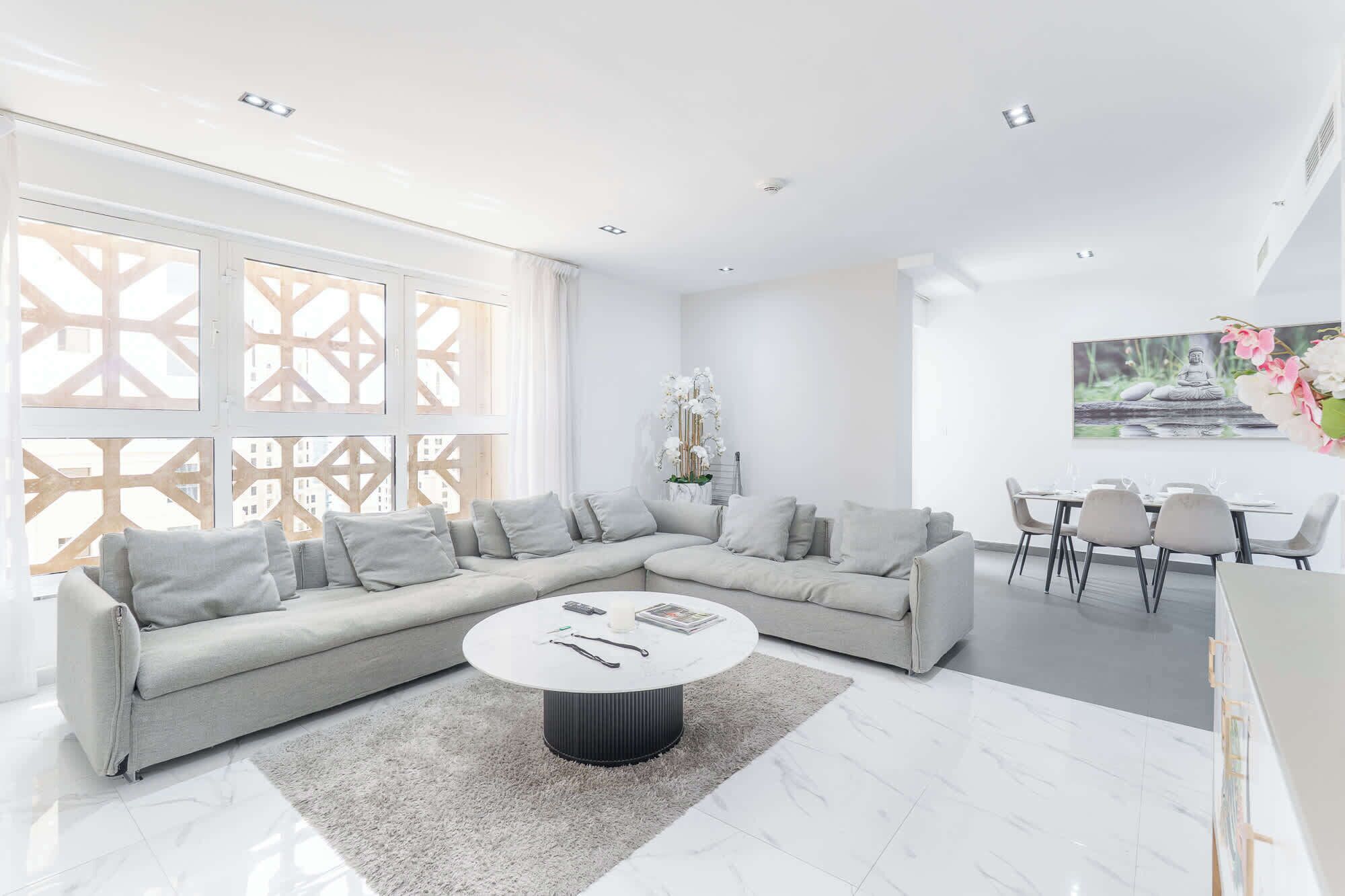 A modern living room with a sectional sofa, a round coffee table, and a dining area with a table and chairs.