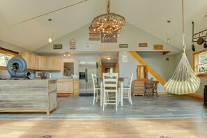 A spacious kitchen with wooden cabinets, a central island, and a hanging light fixture. - Fish + Hike: Wooded Home w/ Deck in Dexter (Dexter)