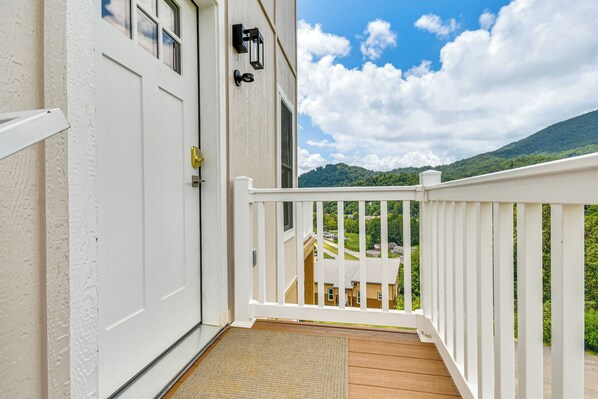 A white door with a doormat, a white railing, and a view of a house and mountains in the background. - Cozy 2br/2ba Mtn Escape w/ Views in Maggie Valley (Maggie Valley)