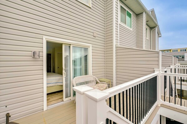 A balcony with a white railing, a wicker chair, and a small table.