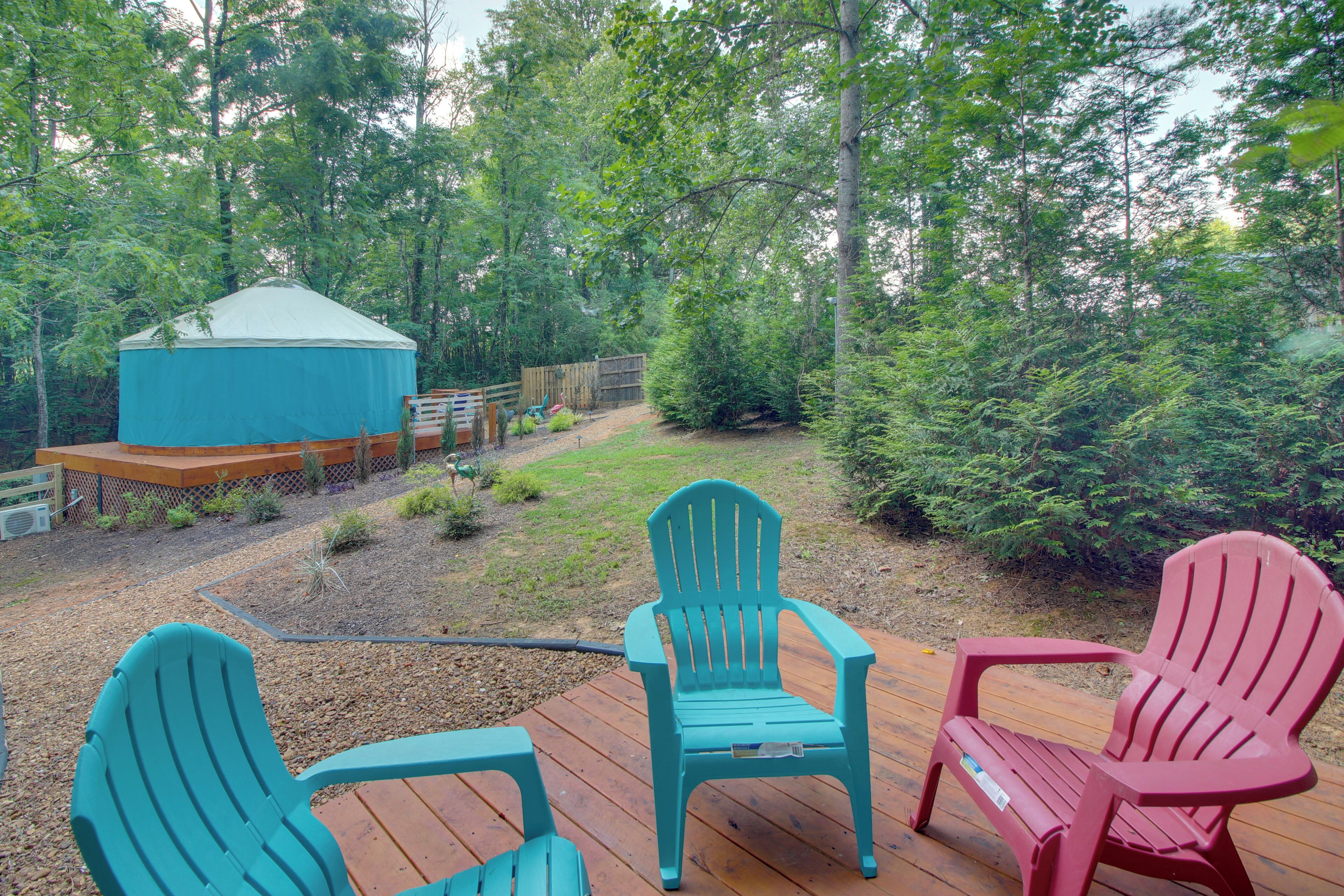 A deck with Adirondack chairs, a blue tent, and a wooden deck.