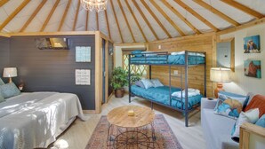 A cozy interior with a bunk bed, a round wooden table, and a bed with a patterned bedspread. - Unplugged Retreat! Unique Yurt w/ Deck in Smokies (Sparta)