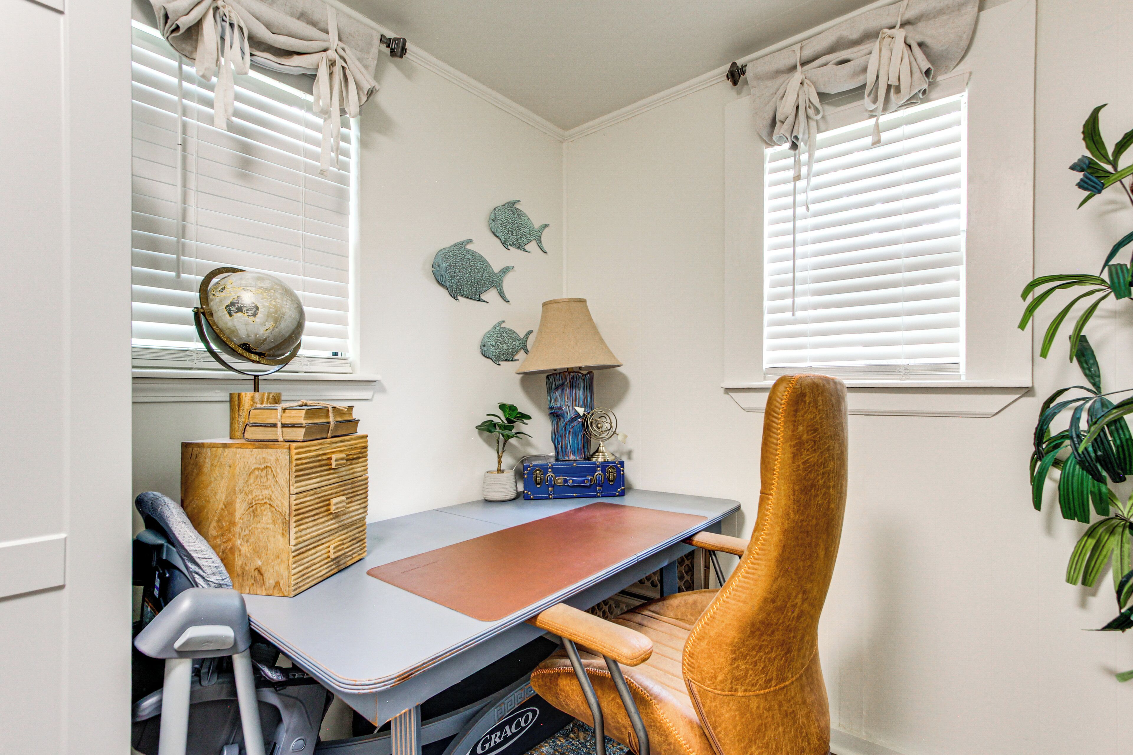 A corner room with a desk, chair, lamp, and decorative items.