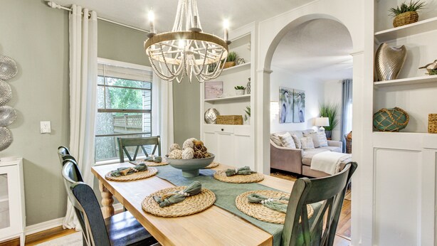 A dining area with a wooden table, woven placemats, and a chandelier. - Hot Tub & Private Backyard! Gulfport Group Getaway (Gulfport)