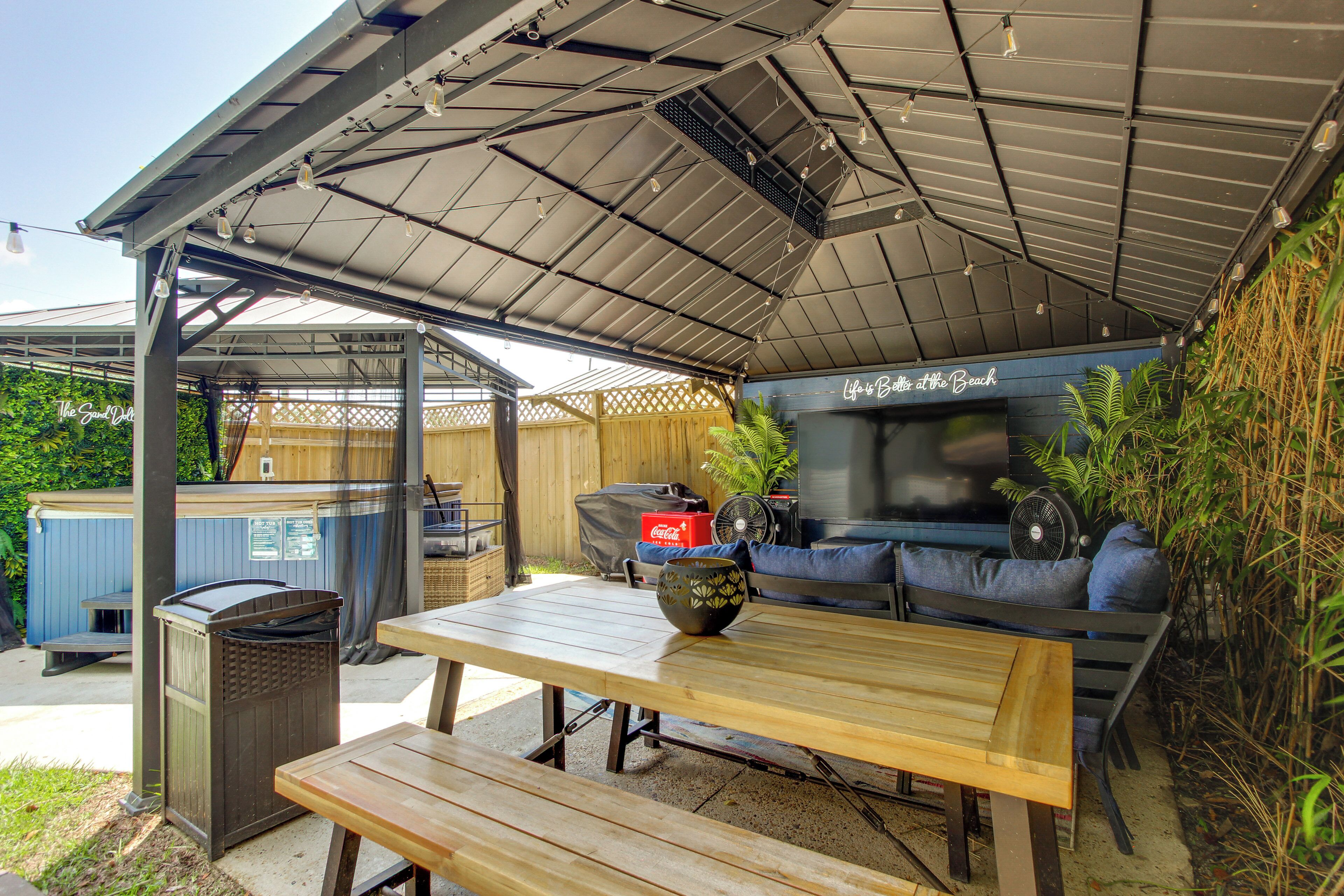 Un patio al aire libre con un área de estar techada, una mesa y un jacuzzi.