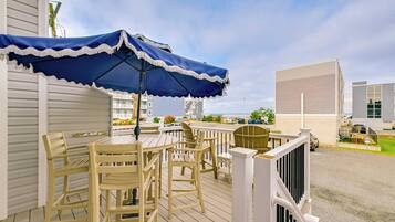 A deck with a table and chairs, a blue umbrella, and a railing.
