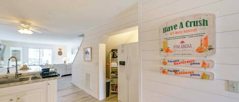 Una cocina moderna con armarios blancos, una isla central y un refrigerador. Un cartel en la pared anuncia bebidas Finlandia.