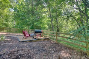 A fenced outdoor area with a grill, red chairs, and a wooden fence. - Unique Dome Home w/ Deck in Smoky Mountains (Sparta)