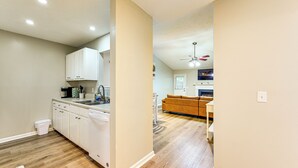 A modern kitchen with white cabinets, a dishwasher, and a wooden floor.