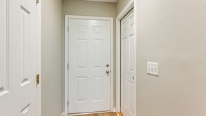 A narrow hallway with white doors and a wooden floor.