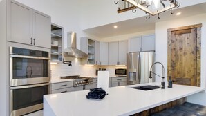 Une cuisine moderne dotée d’appareils électroménagers en acier inoxydable, d’un îlot central et d’un mur d’accent en bois.