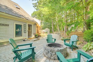 Eine Terrasse mit Adirondack-Stühlen und einer Steinkaminanlage.