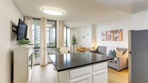 A modern kitchen with a black countertop, white cabinets, and a dining area with a table and chairs. - Prime Location + Ocean View: Myrtle Beach Condo! (Myrtle Beach)