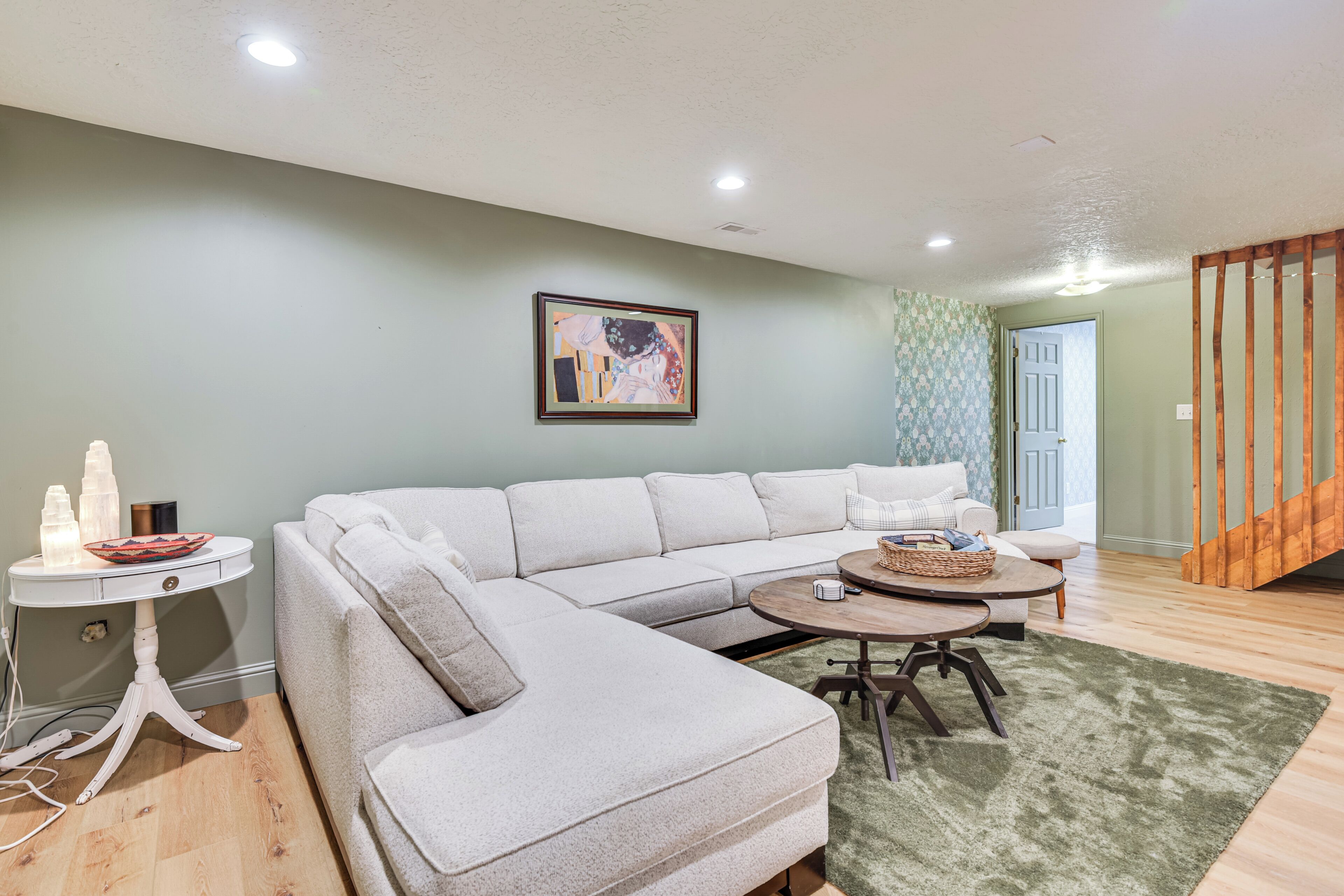 A living room with a sectional sofa, a round coffee table, and a small side table with decorative items.