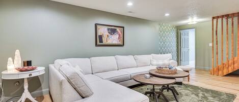 A living room with a sectional sofa, a round coffee table, and a small side table with decorative items.