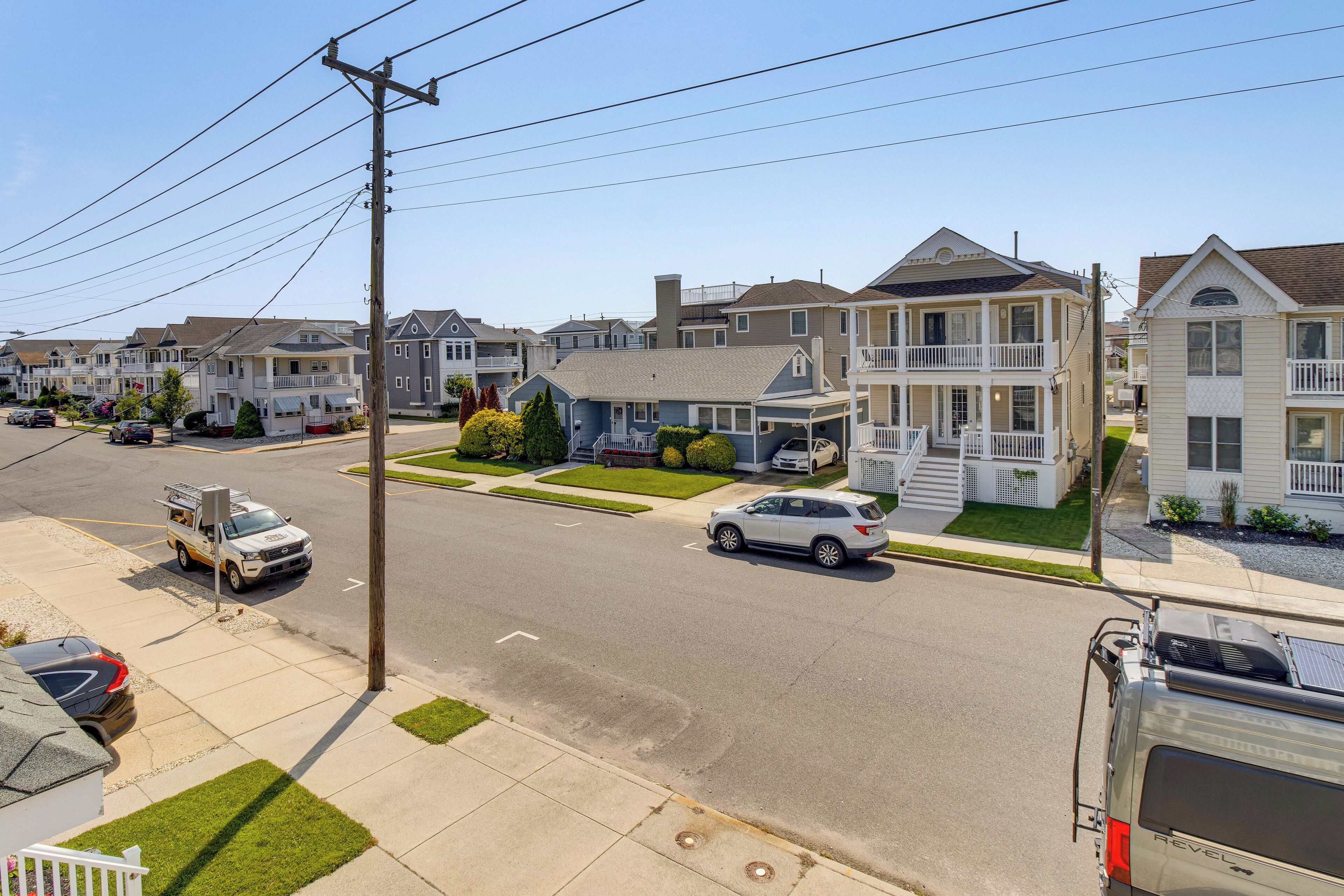 A residential street with houses, a parked utility vehicle, and a white SUV.