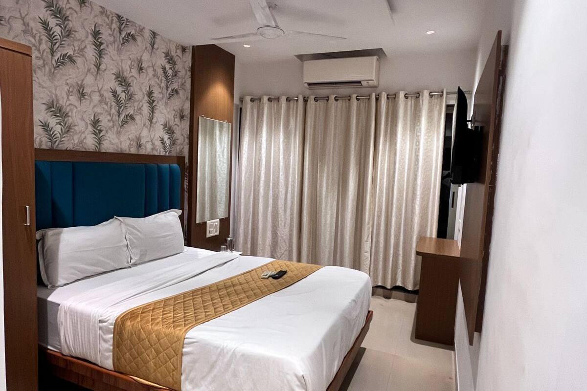 Una habitación de hotel moderna con una cama, un ventilador de techo, un equipo de aire acondicionado y un televisor en la pared.