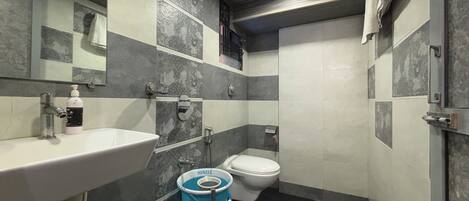 Egy fürdőszoba, amelyben mosdókagyló, WC és egy kék vödör található.