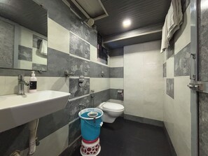 A bathroom with a sink, toilet, and a blue bucket. - Hotel Crystal Palace (Mumbai)