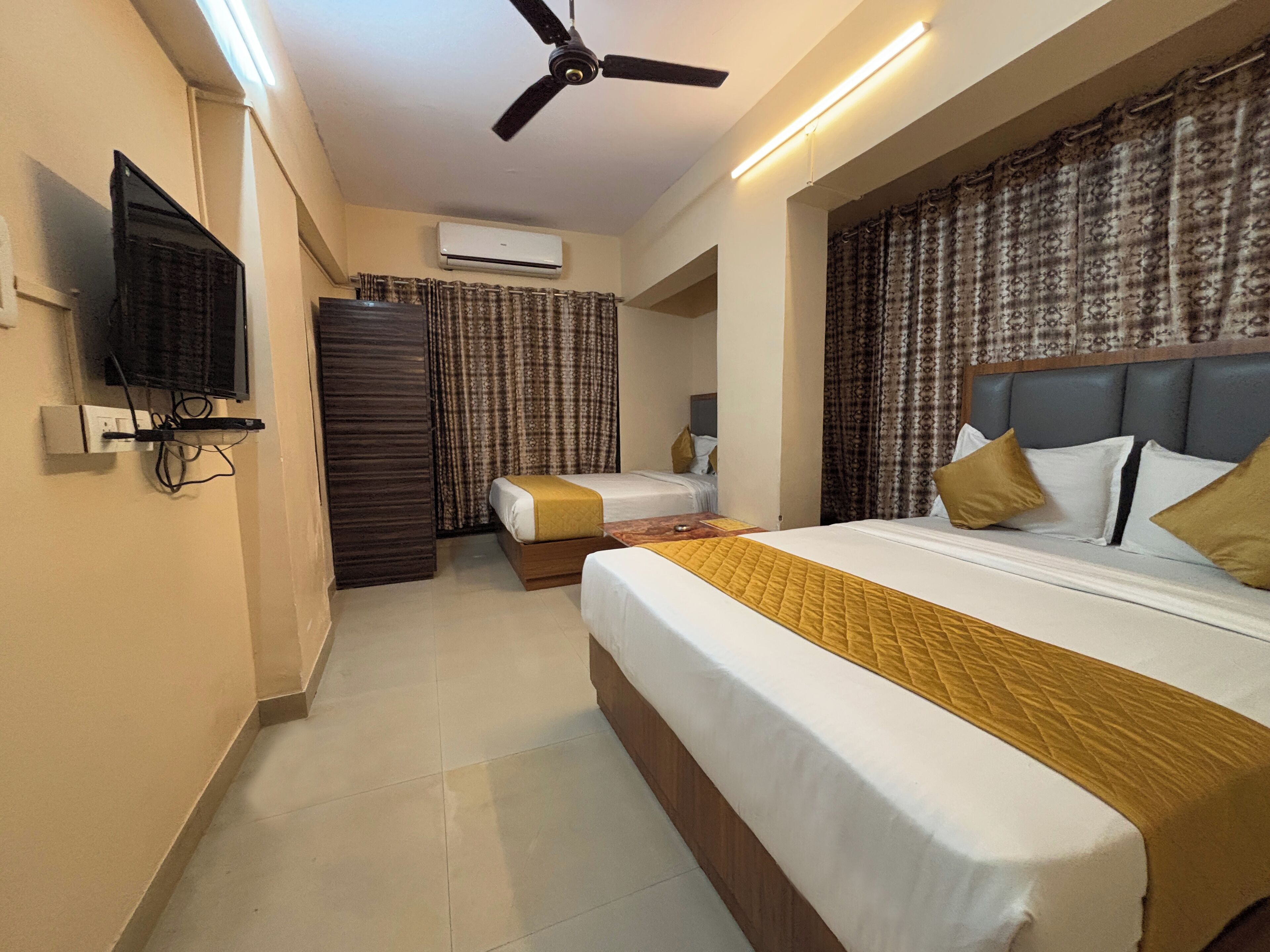 Ein Hotelzimmer mit Bett, Fernseher, Klimaanlage und Deckenventilator.