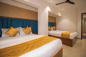 A hotel room with two beds, each with a blue headboard, white bedding, and yellow pillows. - Hotel Crystal Palace (Mumbai)