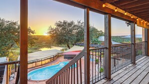 Une terrasse en bois avec une piscine, un espace salon extérieur et une vue sur le coucher de soleil.