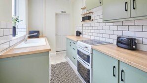 A modern kitchen with light green cabinets, a white sink, a toaster, and a stove. - Host Stay Horner Street (York)