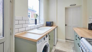 A compact kitchen with a washing machine, a microwave, and a sink. - Host Stay Horner Street (York)