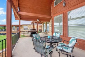 Un patio techado con mobiliario exterior, una parrilla y un muro de piedra.