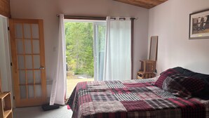 Slaapkamer met een groot bed, een houten deur, een schuifdeur naar een balkon en een lijst met een foto aan de muur.