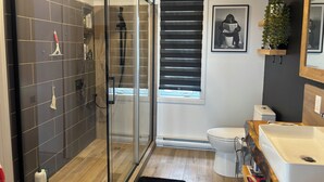 Een moderne badkamer met een douchecabine van glas, toilet en wastafel.
