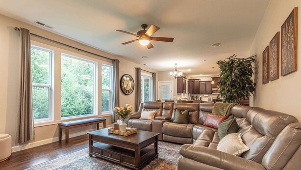 A spacious living room with a leather sofa, a coffee table, and a large window.