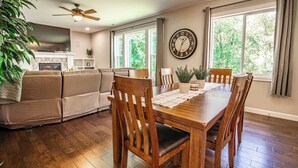 A dining area with a wooden table, chairs, and a clock on the wall.