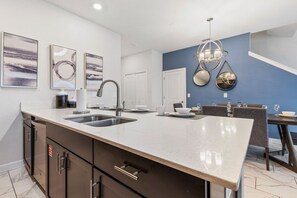A modern kitchen with a large island, stainless steel appliances, and contemporary artwork.