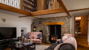 A cozy living room with a stone fireplace, a television, and two sofas.