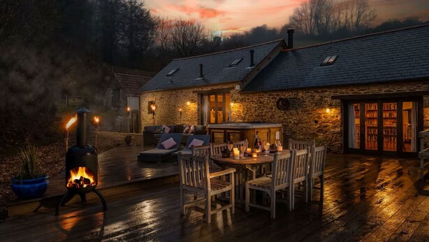 A stone building with a fireplace, outdoor seating, and a library.