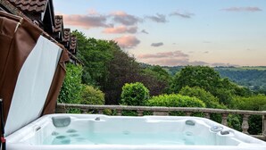 A hot tub on a balcony with a scenic view of a forested landscape.
