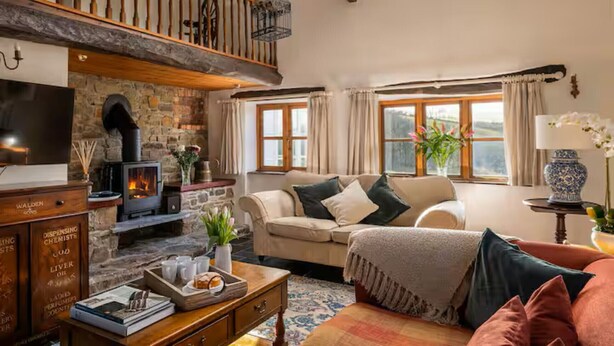 A cozy living room with a stone fireplace, a sofa, a coffee table, and a TV.