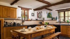 A spacious kitchen with wooden cabinets, a large island with seating, and a clock on the wall.