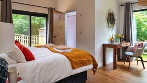 Een slaapkamer met een bed, een bureau en een stoel. Er is een raam met uitzicht op groen.