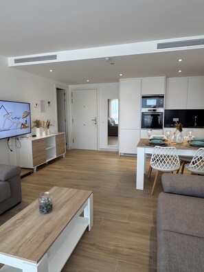 A modern living room with a flat-screen TV, a wooden coffee table, and a grey sofa.