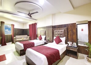 A hotel room with two beds, a sofa, a ceiling fan, a nightstand, and a large mirror.