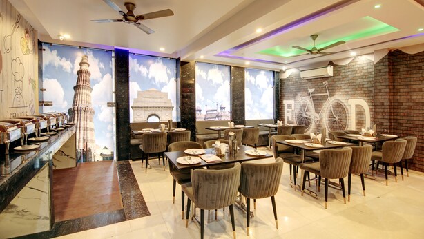 A restaurant with a modern interior, featuring a bar area, multiple dining tables, and chairs. - RTS HOTEL & Spa (New Delhi)