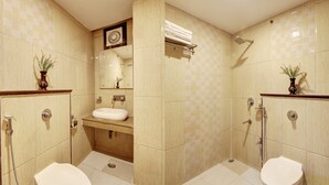 A bathroom with two toilets, a sink, a shower, and a mirror. - RTS HOTEL & Spa (New Delhi)