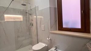 Et moderne badeværelse med et glasafskærmet brusebad, en bidet og et toilet.